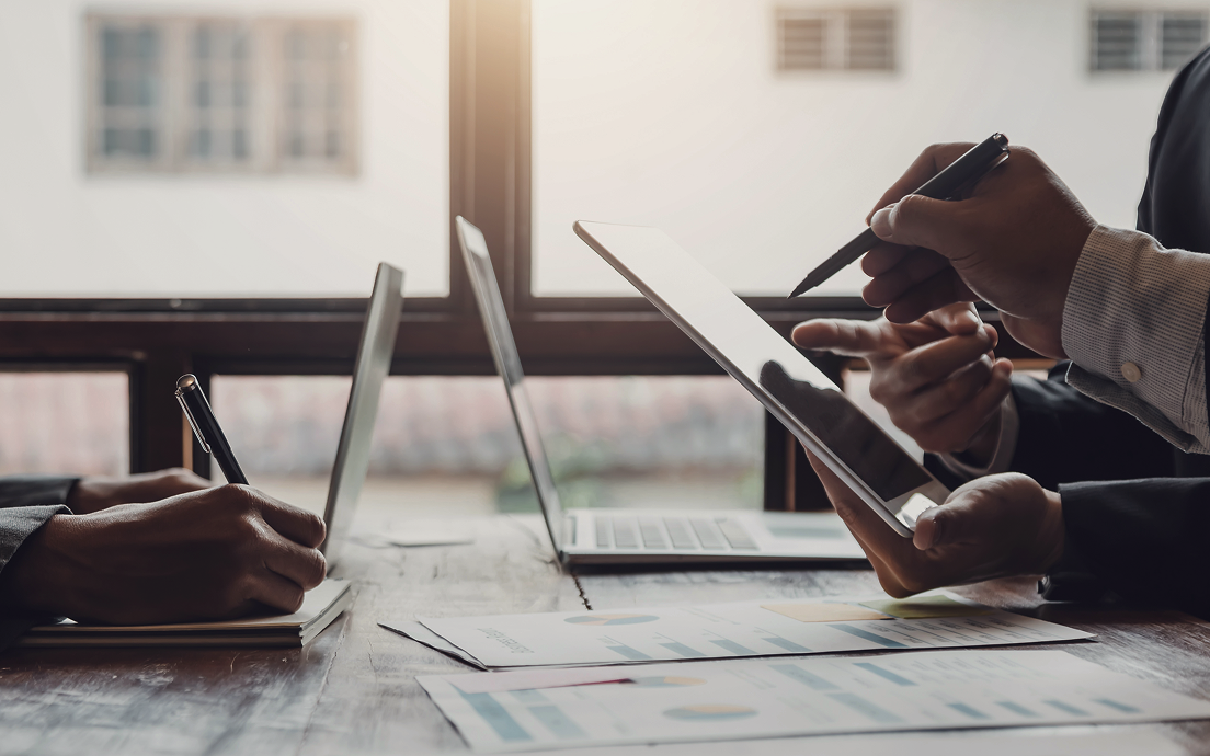 A close up of professionals pointing at an iPad.