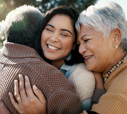 A daughter hugging her elderly parents.