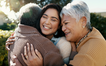 A daughter hugging her elderly parents.