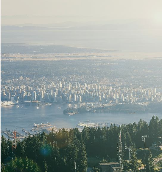 An aerial view of downtown Vancouver with mountains in the background.