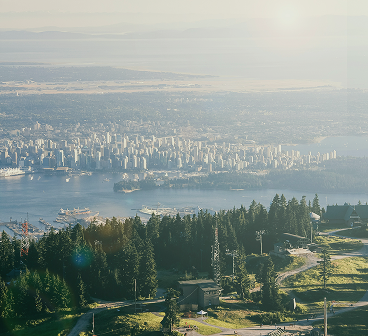 An aerial view of downtown Vancouver with mountains in the background.