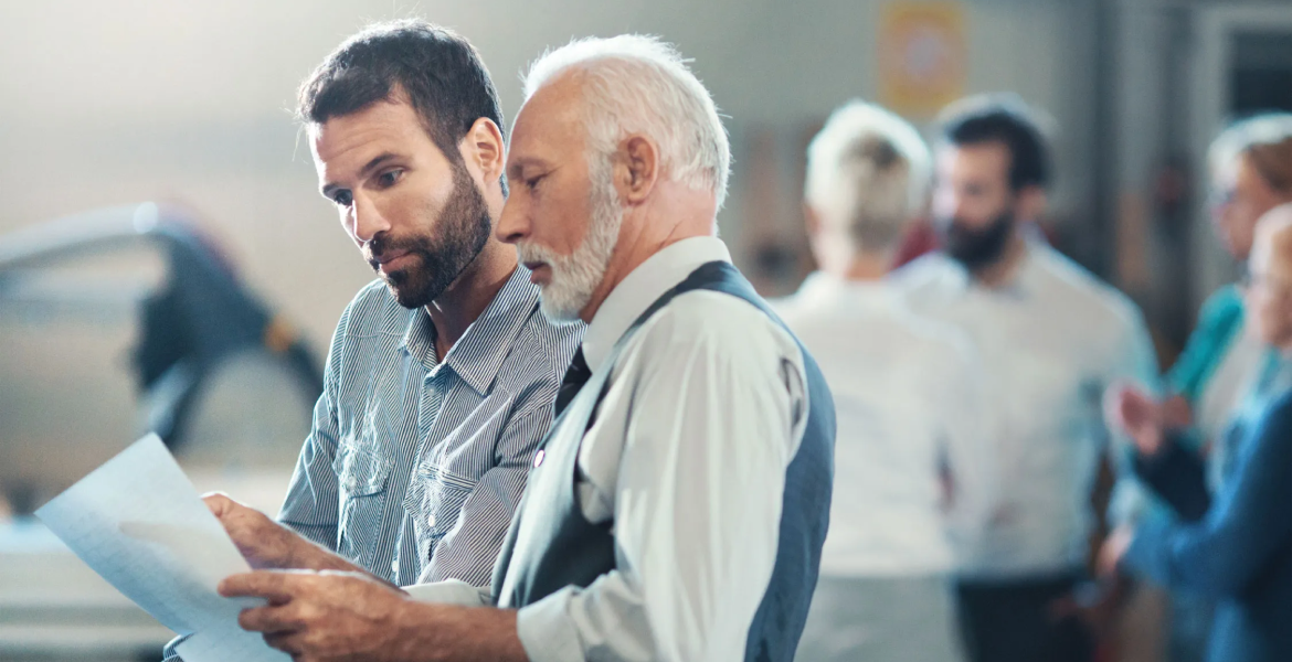 Older businessman discussing documents with a younger colleague