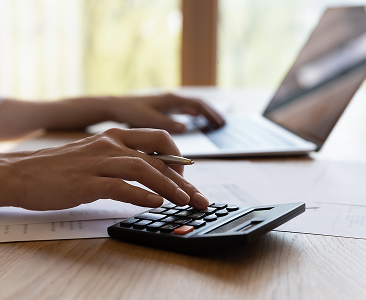 A close up of a wealth professional with their laptop open while using a calculator.