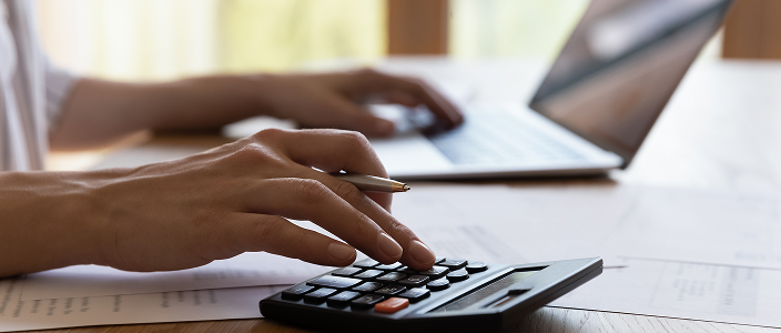 A close up of a wealth professional with their laptop open while using a calculator.