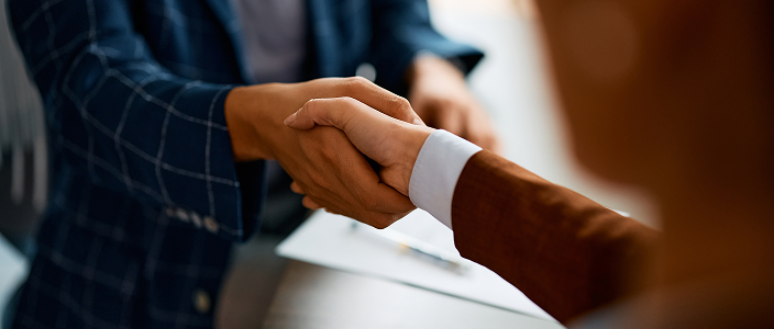 A close-up of a wealth professional and client shaking hands.