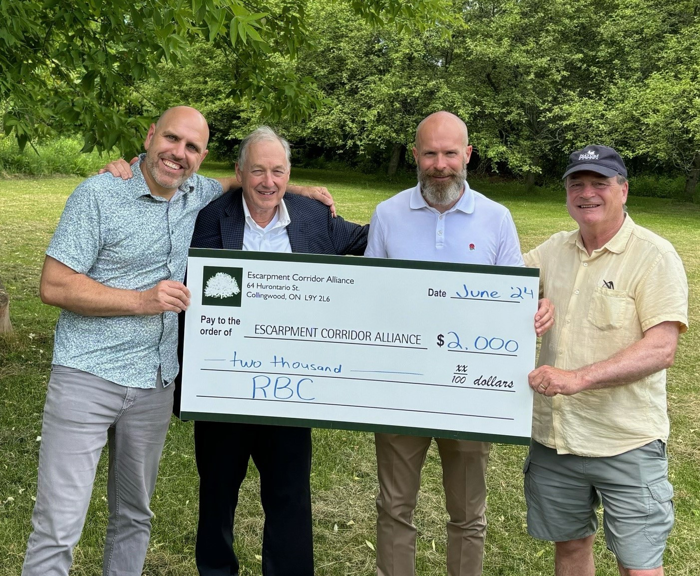 Nick Hamilton stands with 3 others holding a $2000 donation cheque